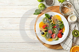 Composition with plate of fresh fruit salad on wooden table, top view