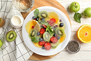 Composition plate of fresh fruit salad on white wooden table, top view