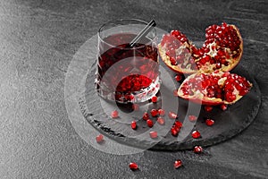 A composition of a pomegranate beverage and cut garnet on a dark gray background. Healthful, natural, fresh red juice.
