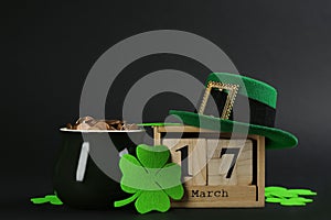 Composition with pot of gold coins and block calendar on black background. St. Patrick`s Day celebration