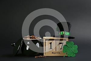 Composition with pot of gold coins and block calendar on black background. St. Patrick`s Day celebration