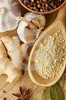 Composition of powder spices on spoon and different sorts of spicies on wooden table background, selective focus