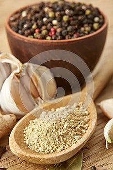 Composition of powder spices on spoon and different sorts of spicies on wooden table background, selective focus