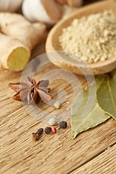 Composition of powder spices on spoon and different sorts of spicies on wooden table background, selective focus