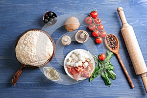 Composition with raw dough and ingredients for pizza on color wooden background