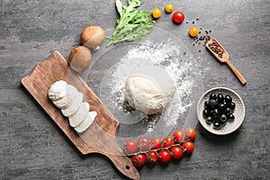 Composition with raw dough and ingredients for pizza on grey background