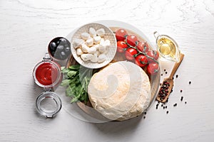 Composition with raw dough and ingredients for pizza on light background