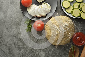 Composition with raw dought and fresh ingredients for pizza isolated on dark background. Copy space. Flat lay food ingredients