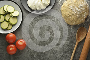 Composition with raw dought and fresh ingredients for pizza isolated on dark background. Copy space. Flat lay food ingredients