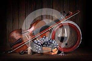 Composition with red grape, wine, violin and barrel