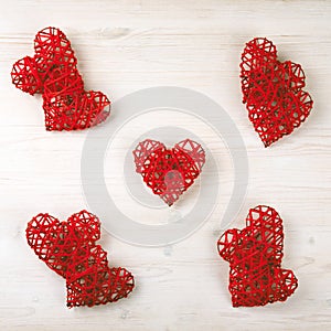Composition of red wicker hearts on the wooden background.
