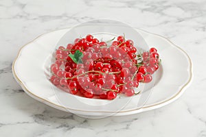 composition of ripe red currant berries on a textured marble