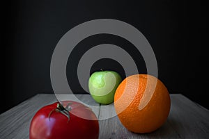 Composition of ripe tomato, green apple and orange