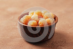 Composition of ripe yellow raspberries in a bowl on a marble