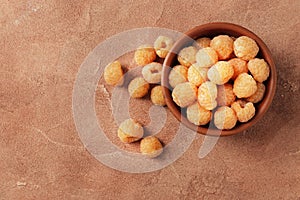 Composition of ripe yellow raspberries in a bowl on a marble