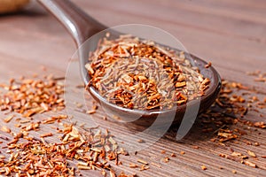 Composition of Rooibos tea is located on a ceramic spoon. Macro