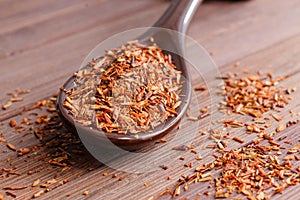 Composition of Rooibos tea is located on a ceramic spoon. Macro