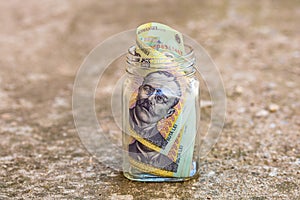 Composition with saving money romanian LEI banknotes in a glass jar. Concept of investing and keeping money, close up isolated