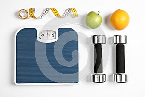 Composition with scales, fruits, tape measure and dumbbells on white background