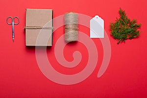 Composition of scissors, box, rope, card and tree branches on red background