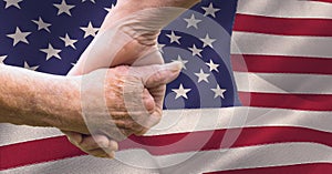 Composition of seniors holding hands over billowing american flag