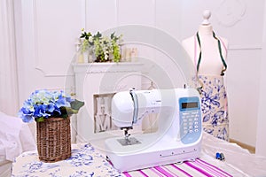Composition from a sewing machine. Mannequin, flowers on a retro table and threads. Sewing supplies and composition with