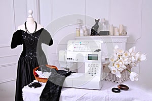 Composition from a sewing machine. Mannequin, flowers on a retro table and threads. Sewing supplies and composition with