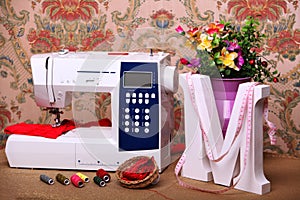Composition from a sewing machine. Mannequin, flowers on a retro table and threads. Sewing supplies and composition with