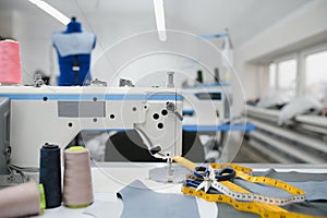 Composition of sewing thread, scissors and tape measure on a white table. Concept of a clothing designer
