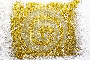 A composition with small letters of the alphabet on beautiful gold glitter. Background and texture of gold glitter. Luxury gold