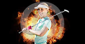 Composition of smiling caucasian female golf player with golf club over flames on black background