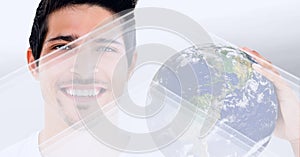 Composition of smiling man holding planet earth on white background