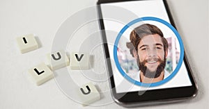 Composition of smiling man over smartphone and i luv u text on white squares