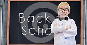 Composition of smiling schoolboy over white text back to school on chalkboard