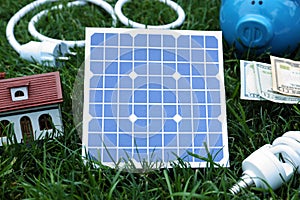 Composition with solar panel, house model and lightbulb