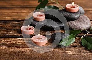 Composition of spa stones, green leaves and burning candles