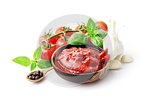 composition of spicy tomato sauce in a wooden bowl with fresh tomatoes, garlic and basil isolated on white background.