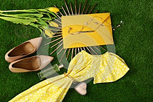 Composition with stylish women`s clothes and accessories for spring on green grass