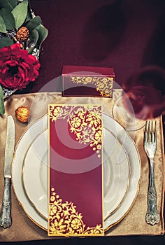 Composition on the table from table setting, fork, knife, glass, white plate with a holiday card