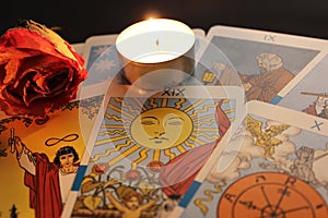 Composition of tarot cards, candle light, dried rose bud