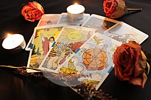 Composition of tarot cards, candle lights, dried rose buds