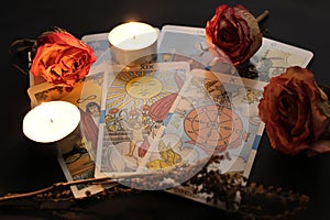 Composition of tarot cards, candle lights, dried rose buds