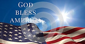Composition of text god bless america over waving american flag on sunny blue sky