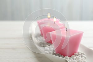 Composition with three burning candles on white table