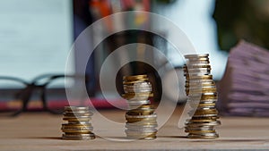 Composition of three stacks of coins near pile of papers, glasses, laptop on desk. Workspace, business, money, banking.