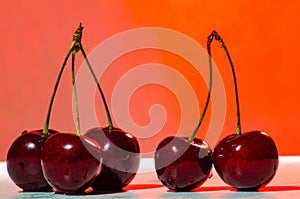 Composition of three and two ripe sweet cherries on a red background