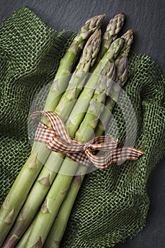 Composition with tied asparagus group on dark stone.