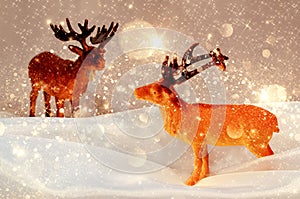 Composition of toy deers among snow and bright stars.