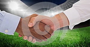 Composition of two businessmen shaking hands over sports stadium