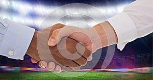 Composition of two businessmen shaking hands over sports stadium